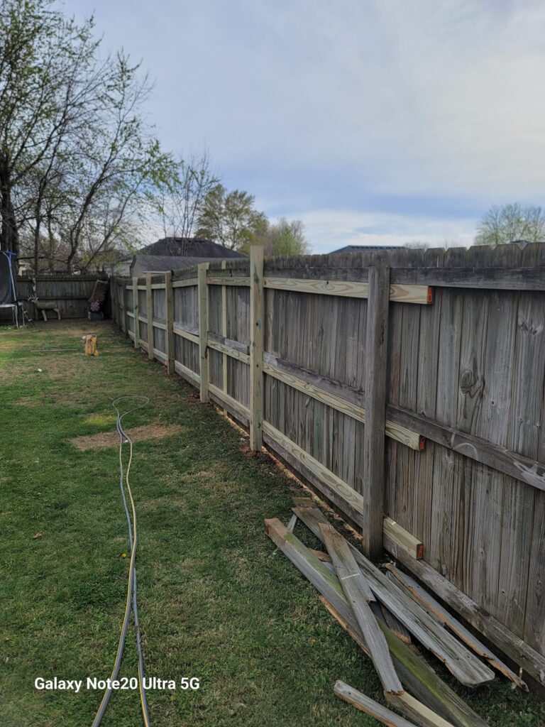 Fence repaired with new planks of wood.